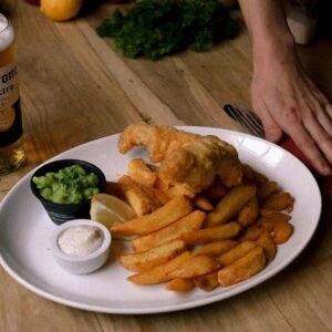 Delicious fish and chips with cold beer served on a wooden table, perfect for a casual meal.