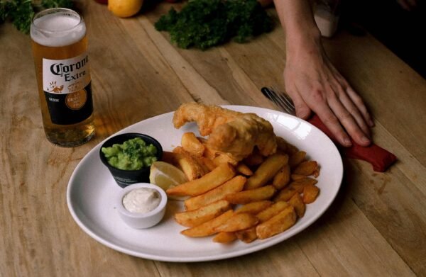 Delicious fish and chips with cold beer served on a wooden table, perfect for a casual meal.