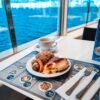 Breakfast setup on a cruise ship with a stunning ocean view through the window.