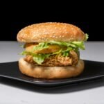 Mouth-watering crispy chicken burger with fresh lettuce on a black plate.