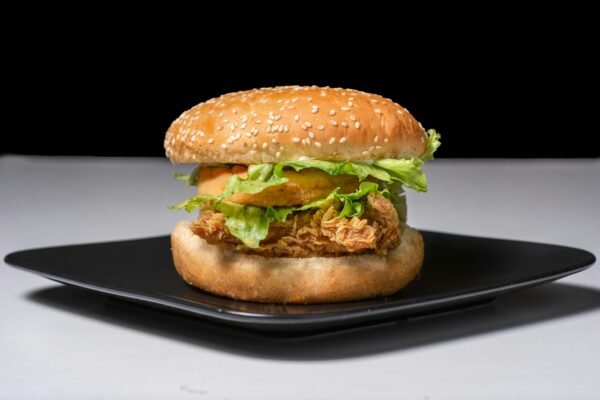 Mouth-watering crispy chicken burger with fresh lettuce on a black plate.