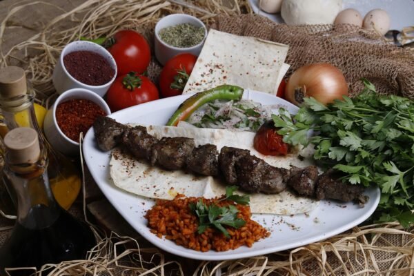 Delicious grilled shish kebab served with fresh vegetables, herbs, and spices on a plate.