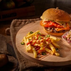 A mouthwatering cheeseburger with fresh fries and coleslaw on a rustic wooden board.