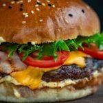 Juicy cheeseburger with bacon, lettuce, tomato, and sesame seed bun.