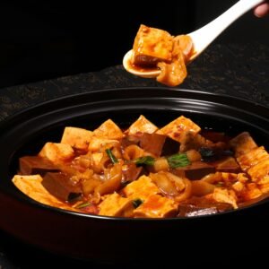 Close-up of a flavorful tofu dish with sauce in a traditional pot, perfect for a culinary experience.