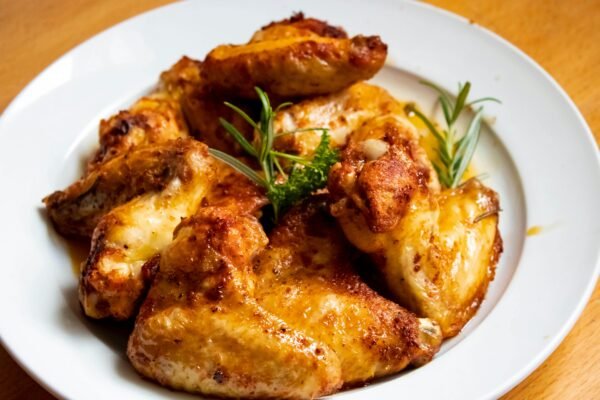 Golden-brown chicken wings garnished with fresh herbs, perfect for a tasty meal.