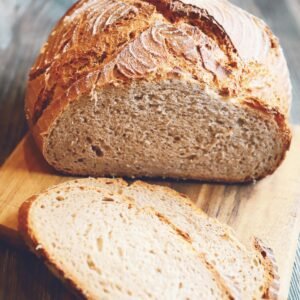 Freshly baked rustic whole wheat bread loaf with slices on a wooden board.