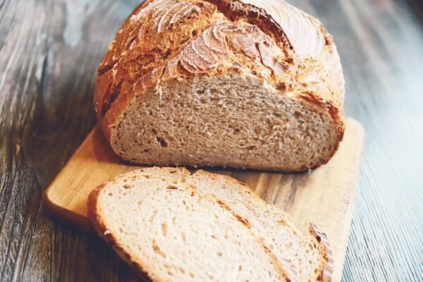 Freshly baked rustic whole wheat bread loaf with slices on a wooden board.