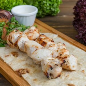 Delicious grilled chicken kebab served on flatbread with fresh herbs, perfect for dinner.