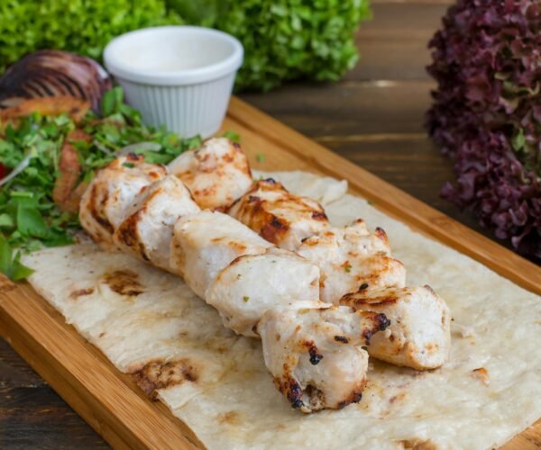 Delicious grilled chicken kebab served on flatbread with fresh herbs, perfect for dinner.