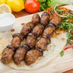 Savor the taste of grilled kebab with eggplant, herbs, and fresh salad on a wooden board.