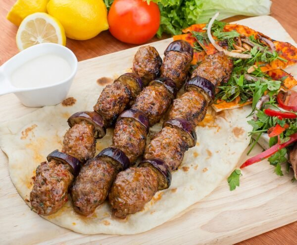 Savor the taste of grilled kebab with eggplant, herbs, and fresh salad on a wooden board.