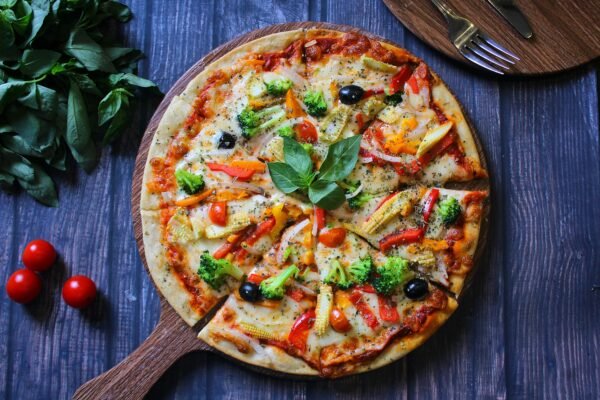 Top view of a colorful vegetarian pizza on a rustic wooden board, perfect for food lovers.