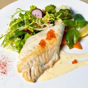 Delicious grilled fish fillet served with fresh mixed greens and sauce on a plate.