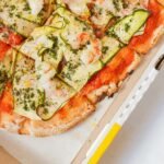 Delicious Italian pizza topped with zucchini and shrimp, captured from above in a cardboard box.