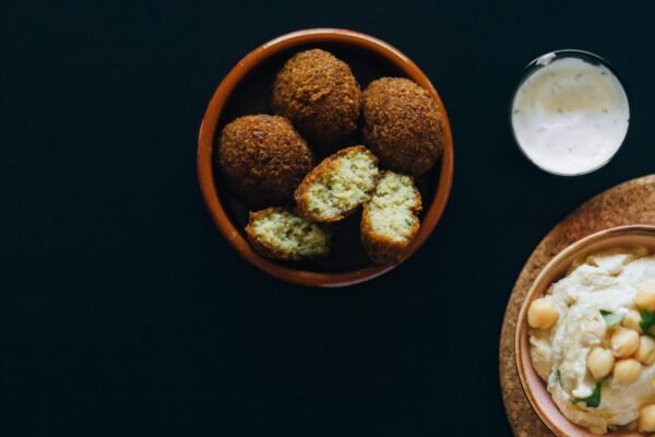 Delicious falafel and creamy hummus served with a side of tzatziki sauce, perfect for vegan meals.