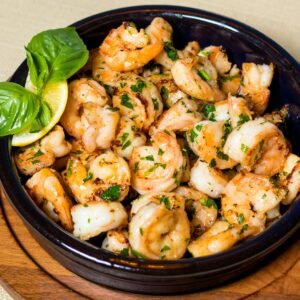 Delicious grilled shrimp with herbs and lemon in a wooden bowl.