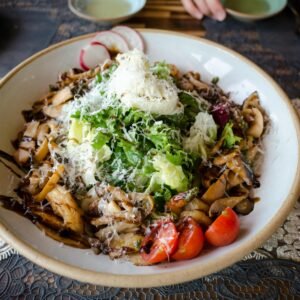 A delicious vegan salad featuring lettuce, radish, tomatoes, mushrooms, and cheese.