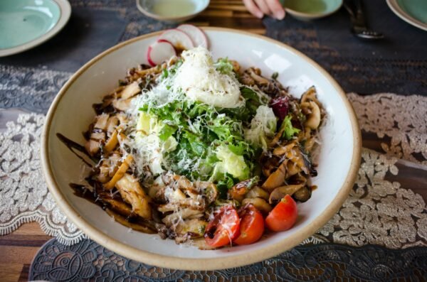 A delicious vegan salad featuring lettuce, radish, tomatoes, mushrooms, and cheese.