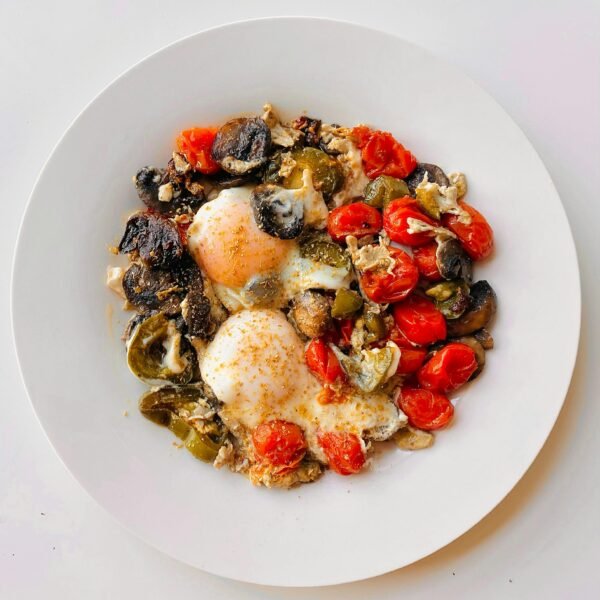 A savory Mediterranean dish featuring poached eggs, roasted tomatoes, mushrooms, and peppers.